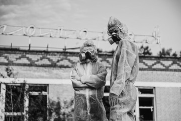 Two scientists put on a respirator and a radiation protective suit. Stern look into the camera from...