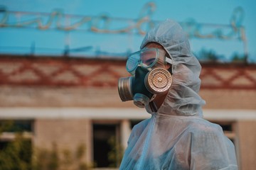 The scientist put on a respirator and a white protective suit against radiation. Close-up profile...