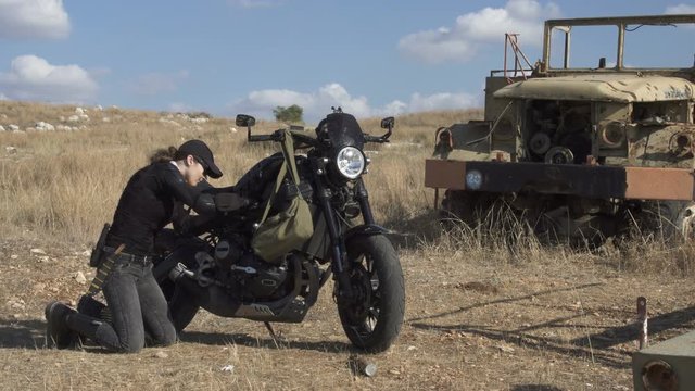 Young biker woman repair fixing  her motorcycle  on the old desert  road
