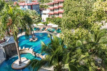 Fototapeta na wymiar resting area in the tropical hotel, view from balcony. sun deck of resort. Swimming pool view and palm trees. take a rest time concept.