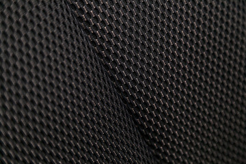 Close-up black car seat trim. Soft rough carbon fabric texture.