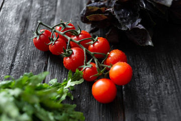 juicy appetizing cherry tomatoes with basil arugula lie on a vintage wooden table