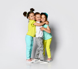 Studio portrait of children on a light background: full body shot of three children in bright clothes, two girls and one boy. 
