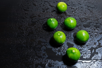 Fresh limes on wet wooden table background. Selective focus.