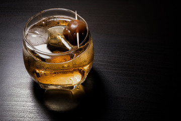 Umeshu or Japanese plum wine in glass with ice on wooden table. Selective focus.