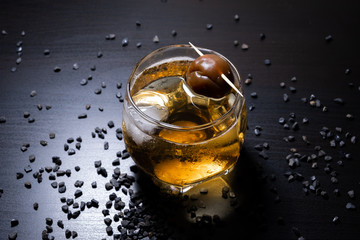 Umeshu or Japanese plum wine in glass with ice on wooden table with black pebbles. Selective focus.