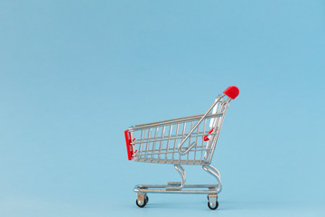 Shopping cart on blue background. Minimalist style. Creative design. Copy space. Sale, discount,...
