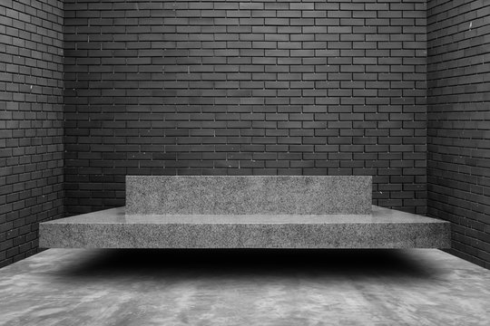 Gray marble bench on the cement floor with black brick wall background. Loft style concept.