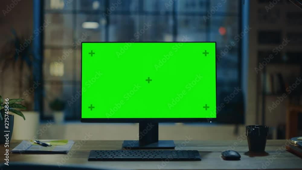 Aufkleber Desktop Computer with Mock-up Green Screen Standing on the Wooden Desk in the Modern Creative Office. In the Background Warm Evening Lighting and Open Space Studio with City Window View. Zoom In Shot