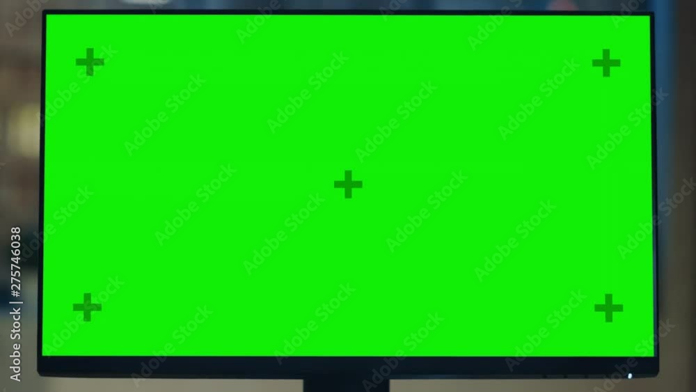 Poster Desktop Computer with Mock-up Green Screen Standing on the Wooden Desk in the Modern Creative Office. In the Background Warm Evening Lighting and Open Space Studio with City Window View. Zoom Out Shot