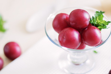 plums lie in a glass cream bowl on the table, lemon cut into slices, fresh mint leaves, healthy foods, dietary berries and fruits,