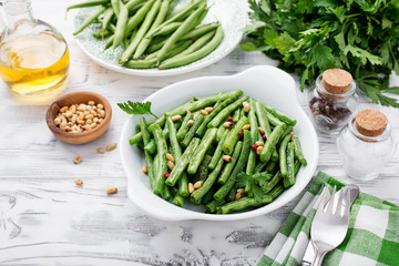 Sauteed green beans with pine nuts in a baking dish, healthy side dish.