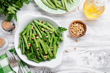 Sauteed green beans with pine nuts in a baking dish, healthy side dish.