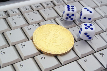 Golden bitcoin coin and dices on laptop computer keyboard