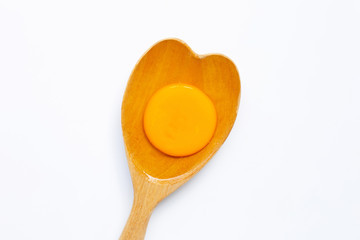 Egg yolk on wooden spoon on white