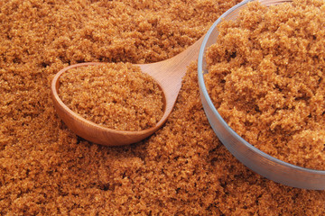 Wooden spoon and glass bowl with dark brown sugar