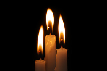 Three burning candles in darkness. Memorial symbol.