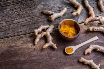 Fresh turmeric and powder curcumin on old wooden background