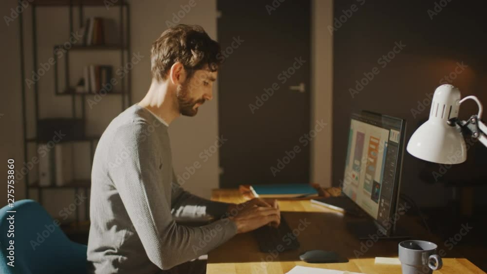Poster Designer Sitting at His Desk in Office Studio Working on a Desktop Computer with Smartphone Software Development Application on Screen. Energetic Fast Paced Movement. 360 Degree Tracking Arc Shot