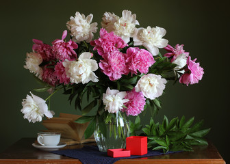 beautiful bouquet of peonies on the table and a box with a gift.