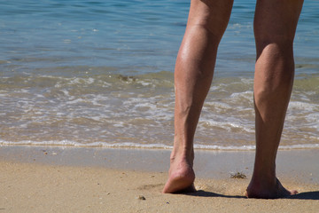 Fototapeta na wymiar feet of man walking along the shore of the beach