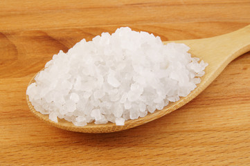 Sea salt in wooden spoon close up