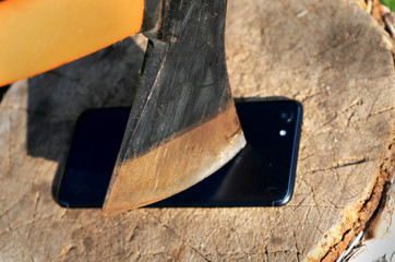 Destroy innovation. Vandalism act. Smartphone on the stump. Smartphone near the ax. 