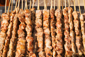 Chicken meat skewers being grilled in a barbecue.