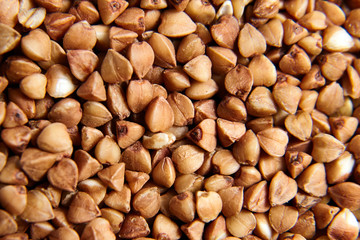 Buckwheat grains. Grechka. Dry brown kernel as background. Selective focus