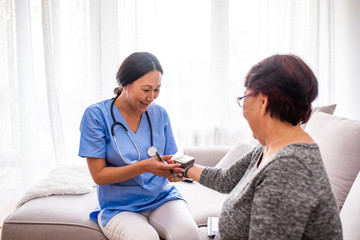 Close positive relationship between senior patient and caregiver. Happy senior woman talking to a friendly caregiver. Young pretty Asian caregiver and older happy woman