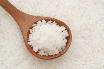 Wooden spoon on sea salt background