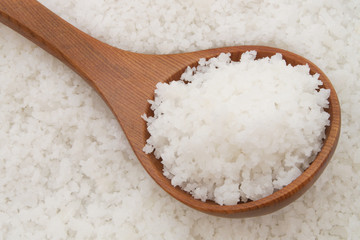 Wooden spoon on sea salt background