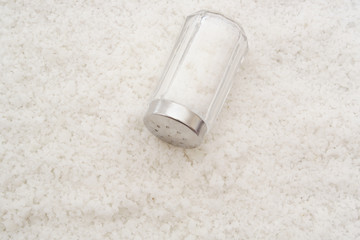 Salt shaker on sea salt background