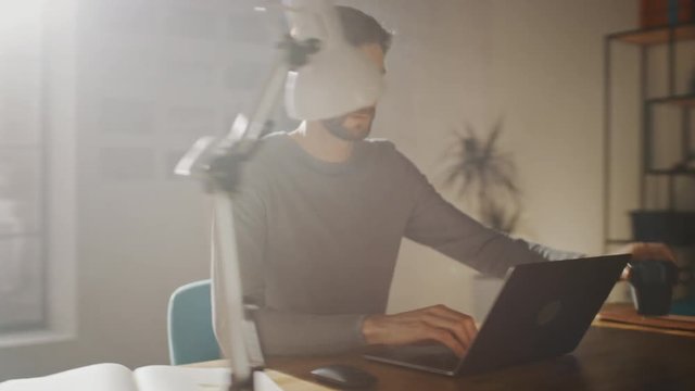 Professional Creative Man Sitting At His Desk In Home Office Studio Working On A Laptop, Concentrated Man Using Notebook Computer. Energetic Fast Paced Movement. 360 Degree Tracking Arc Shot