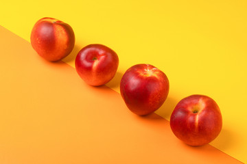four nectarines on orange yellow background