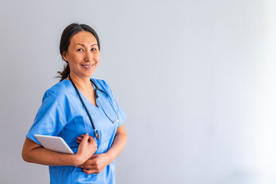 Nurse who is working her shift in a hospital. Close up portrait of female healthcare worker standing in hospital corridor. Asian woman in hospital hallway staring at camera.