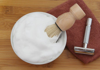 Shaving accessories on wooden background. Razor, brush, towel and foam in bowl. 