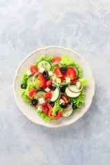 Greek salad. A plate of fresh salad with lettuce, feta cheese, tomatoes, cucumbers, onions and olives, shot from the top with copy space