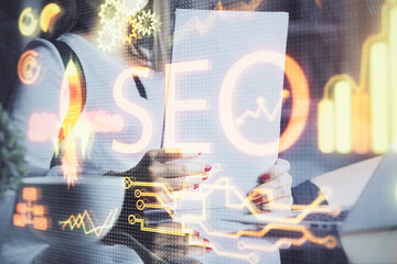 Double exposure of woman's hands making notes with SEO icon. Concept of Search engine optimization