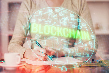 Cryptocurrency hologram over woman's hands writing background. Concept of blockchain. Multi exposure