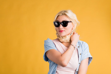 Close up photo of beautiful woman in sunglasses isolated on yellow background