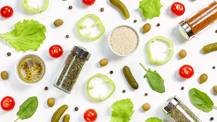 Salad ingredients layout on white desk. Food pattern with cherry tomatoes, cucumbers, greens, pepper and spices