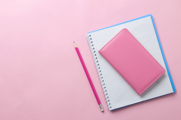 several notebooks and a pink pencil on a bright pink background. top view. office tools