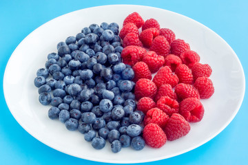 Juicy raspberry and blueberries on white and blue background