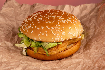 Burger bun with sesame and chicken meat on wrapping paper