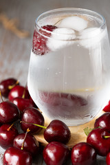 a glass of mineral water with cherry. on grey background