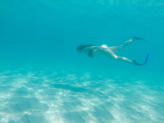 Fit girl in bikini freediving under the sea