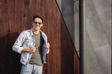 Young man posing in his sunglasses next to the wall