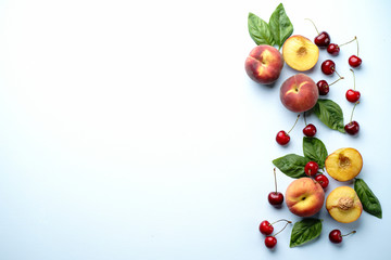 Culinary background, food blog, recipe concept. Layout of ripe sweet cherries and peaches on blue table. Seasonal dessert. Delicious vegetarian meals and diet concept