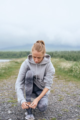 Woman ties up shoe laces on the trail